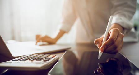 Fototapeta premium Hand of a business woman with a pen and a smartphone working on documents on the table in office.