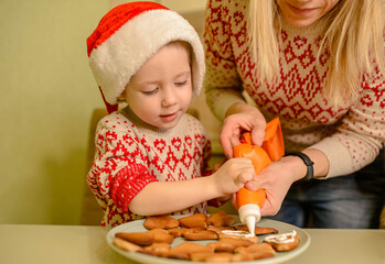 Adorable boy bake homemade festive gingerbreads. Homemade baking