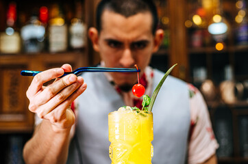 Bartender putting a cherry on a tiki cocktail.