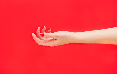 Female hand on a red background. Red manicure. The photo was taken with selective focus and has a noise effect.