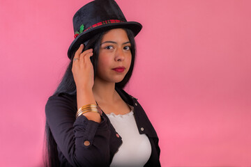 A beautiful Colombian woman with a Christmas hat next to a pink wall