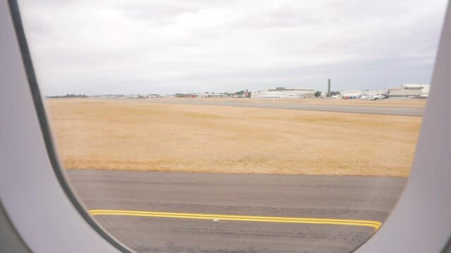 slow motion push in shot of airport and dry grass around runway while plane waits to take off