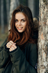 Fototapeta premium woman in a warm jacket near a tree in the forest attractive travel look