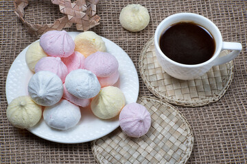 Homemade meringue kisses and coffee cup. Meringue cookies on natural sackcloth background.
