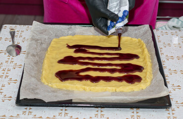 Spread the jam on top of the prepared dough on the kitchen table with a spoon.