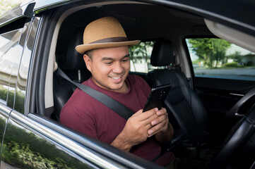 Young asian man using smartphone while driving car.