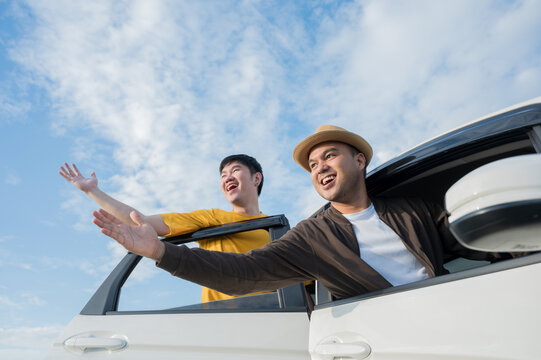 Two Asian friends travel by car on a clear day, beautiful blue sky. They was happy along the way trip.