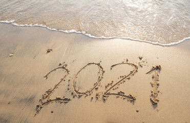 Sea wave wipe away 2021 Text writing on white sand Tropical beach in the morning Beautiful light sunrise on beach and wave crashing on sandy shore.