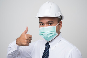 Young asian manager civil engineer helmet hard hat wearing protection mask safety from virus and pollution showing thumbs up on isolated white background.