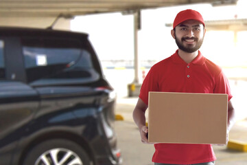 Smiling delivery man holding cardboard box