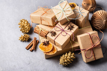 Christmas gifts in kraft paper and eco friendly decorations on grey concrete background