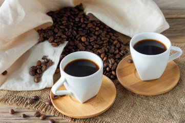 Two cups of freshly brewed espresso on wooden table. coffee beans on light wooden table, rustic style, homemade.