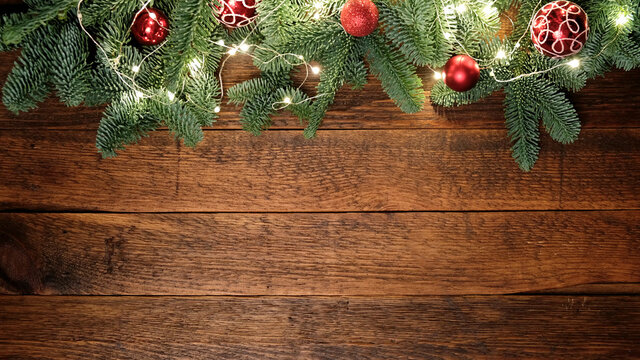 Christmas, New Year background composition with copy space. Fir tree with decorations and Christmas lights on rustic wooden background. Top view