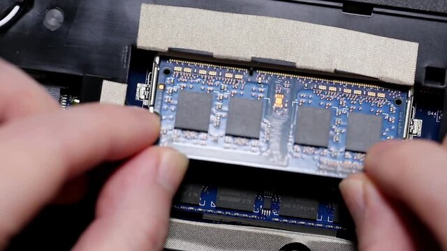 Close up man installing a ram into the laptop