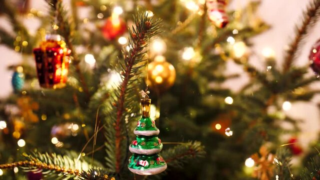 Geschm&uuml;ckter Weihnachtsbaum mit Christbaum Kugeln und russisches Spielzeug am Tannenbaum h&auml;ngt und wackelt im Hintergrund Lichterkette X-Mas Advent Weihnachtsmann Geschenke 4k