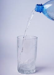 Pouring water from a bottle into a glass on a blue background