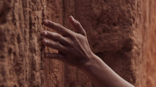 Close up of a hand sliding along the stone walls. Man's hand sliding across the rocky cave walls. 