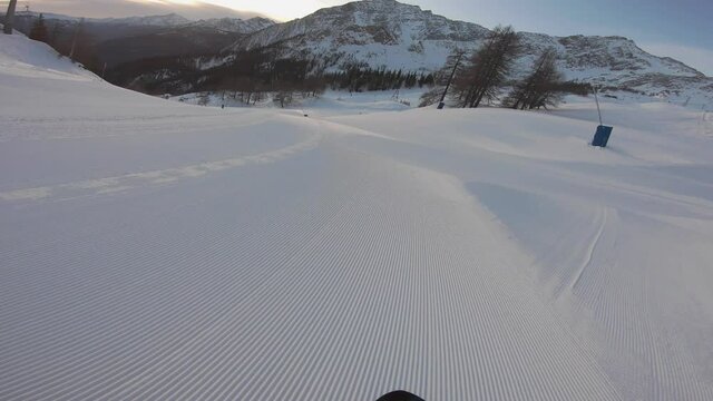 Impressive bottom ground level point of view of pro expert snowboarder riding down a ski slope at dawn or sunset - Downhill skimming the snow POV action cam video at Pra Neyron, Courmayeur, Mont Blanc