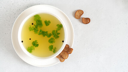 Homemade turkey bone broth in white bowl with parsley leaves, peppercorns and croutons. Health benefits. Collagen is good for joints. Collagen provides the body with amino acids. Top view.