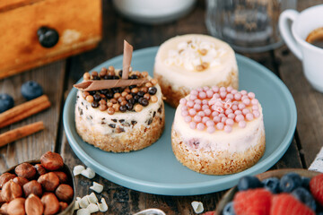 Chocolate cakes on a plate with berries and nuts. Composition of desserts on a wooden table.