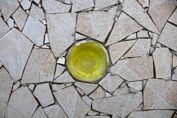 evocative image of a mosaic texture of irregularly shaped white tiles with the bottom of a yellow...