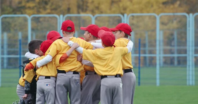 Baseball at school, team of boys baseball players in yellow uniforms get hugs and rejoices in victory, successful game, positive emotions, 4k Slow Motion.