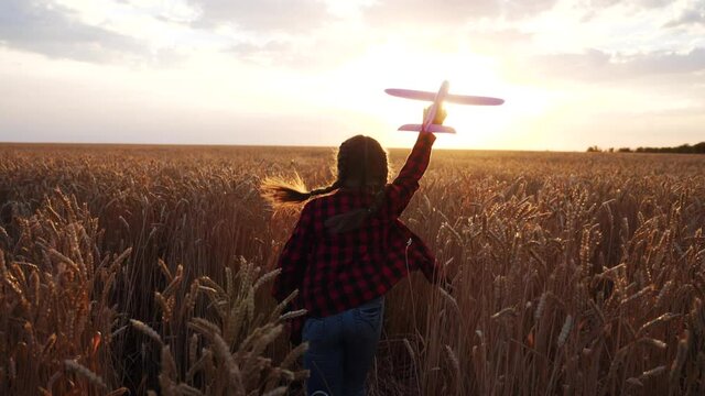 girl kid run with a toy airplane at sunset. kid dream childhood concept. girl child runs with an airplane toy silhouette in the park. carefree child dream outdoors silhouette. people in fun the park