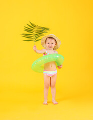 Cute baby girl with inflatable ring and tropical leaf on color background