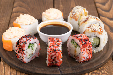 sushi on a plate and sauce, on a wooden background