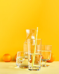 Citrus fruits distorted through water and glass on yellow background. Art trendy minimalist still life. Healthy lifestile. Vitamin C.