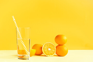 Citrus fruits distorted through water and glass on yellow background. Art trendy minimalist still...
