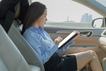 Businesswoman inside a car using a tablet for working.