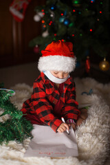 a child in red clothes is sitting waiting for the new year. the concept of celebrating Christmas at midnight. holiday costume. a girl writes a letter to Santa Claus. wish list