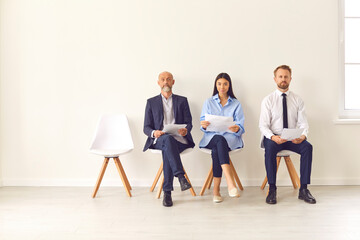 Group of business people sitting on chairs in the lobby and waiting for an interview.