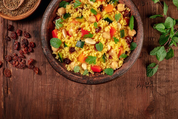 Couscous with ingredients, overhead flat lay shot on a dark wooden background with a place for text