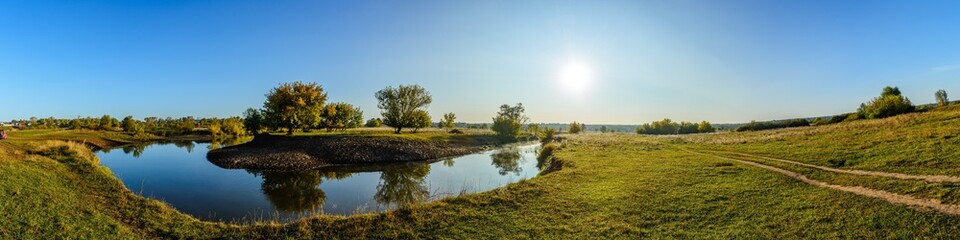 Panorama of the bend of the river at the moment of sunrise in a clear sky, in the right part of the panorama cargo transport