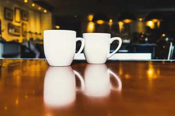 Two white tea mug on the table with reflection at cafe. Beverage. Copy space. Lighting background.
