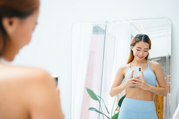 Fototapeta na wymiar Beautiful sporty asian woman wearing sportbra taking photo at mirror.