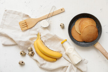 Tasty banana pancakes with ingredients on white background