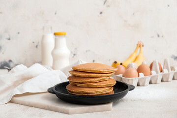Frying pan with tasty banana pancakes on table