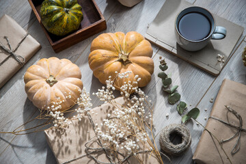 Packaged and bandaged gifts, pumpkins, a cup of tea and dried plants are on the table. Preparing for the birthday.