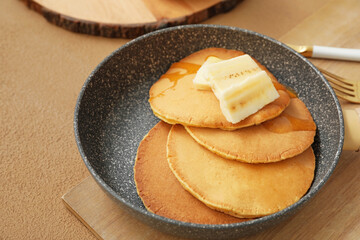 Frying pan with tasty banana pancakes on table