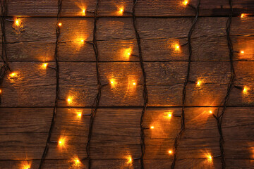 Glowing Christmas lights on dark wooden background