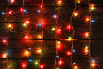 Glowing Christmas lights on dark wooden background