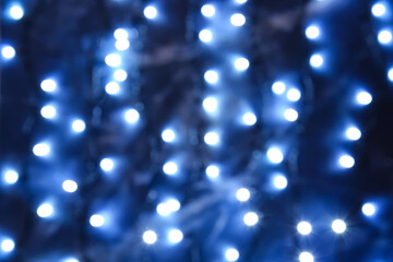 Glowing Christmas lights on dark background, blurred view