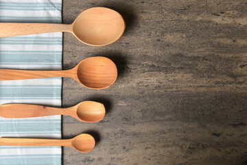 Wooden spoons with napkin on a rustic wooden table. Flat lay, top view, copy space banner.