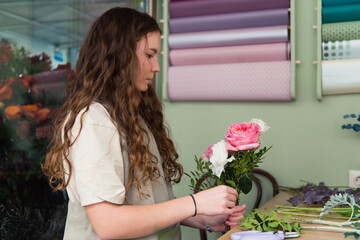 Young woman florist makes a bouquet at workplace, small business concept, lifestyle