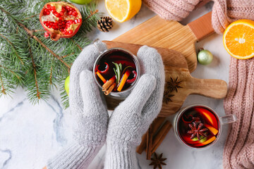 Female hands with glass cups of tasty mulled wine on white background