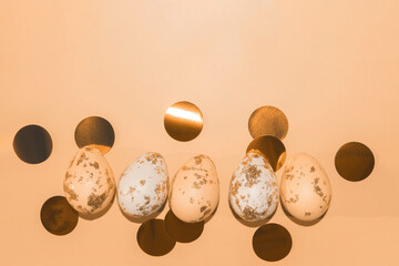 peach and white Easter eggs painted with gold with round golden confetti