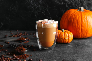 Glass of pumpkin cappuccino on dark background